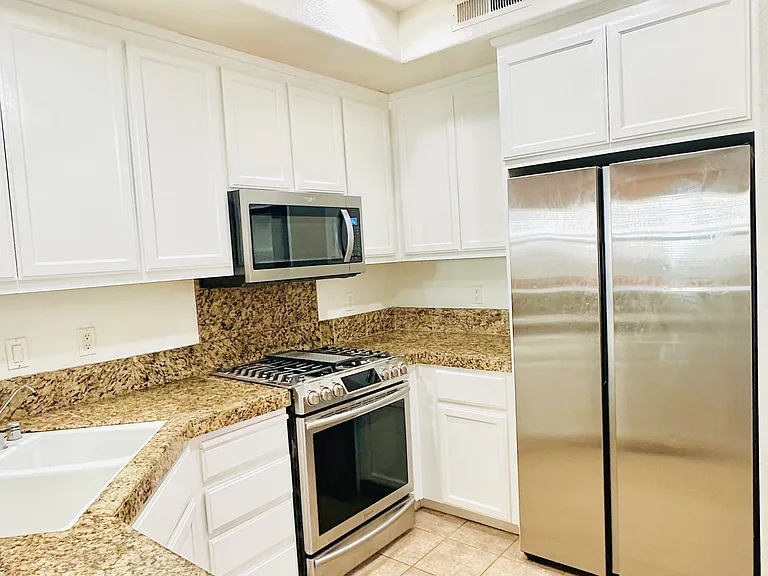 Kitchen equipped with sparkling granite countertops, an elegant tile backsplash, brand-new refrigerator, premium stainless steel appliances, and a high-end Samsung gas stove.