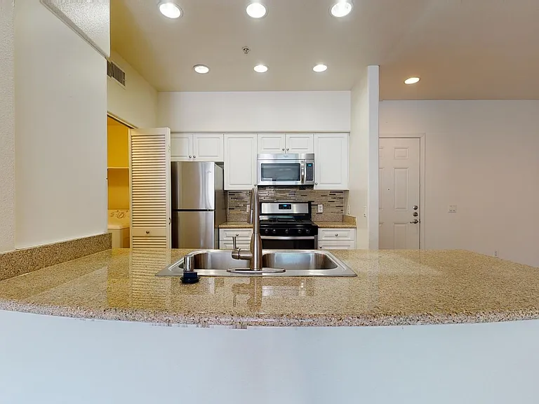 Apartment kitchen with stainless steel appliances, granite countertops, and wood-style flooring.