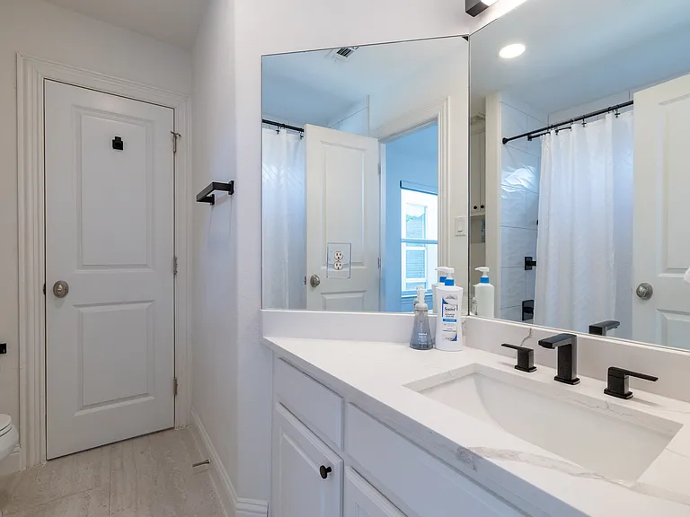 Modern full bathroom with sleek black fixtures and a large mirror.