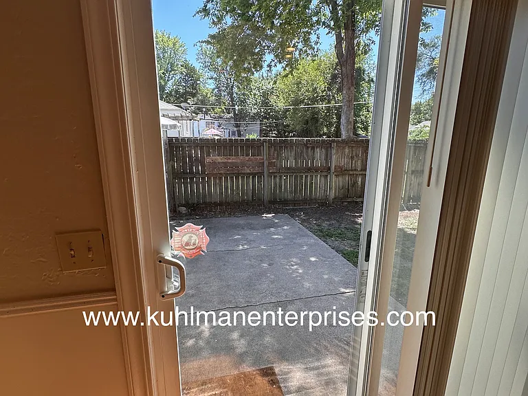Sliding door to back patio and fenced back yard with mature trees.