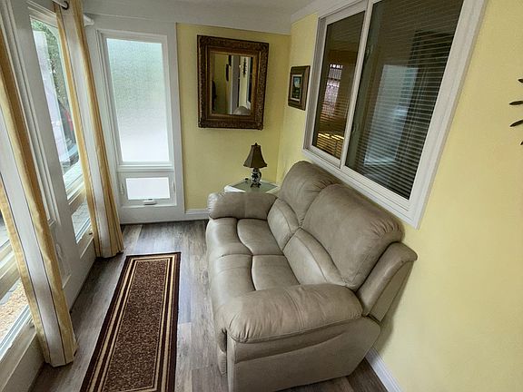 Sun room upon entering front door, with leather love-seat and side table.
