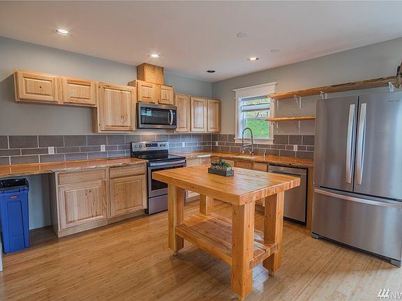 Newly remodeled kitchen with custom, live edge slab countertop and shelves.