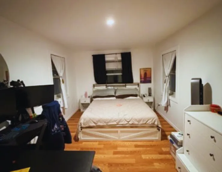 Ample bedroom with large windows and room for a desk and wardrobe.