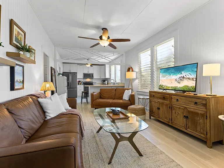 The living room includes an Italian leather sofa and loveseat and one chair, TV, ceiling fan, windows and an AC unit. The living room opens to the lanai and blends seamlessly with the kitchen.