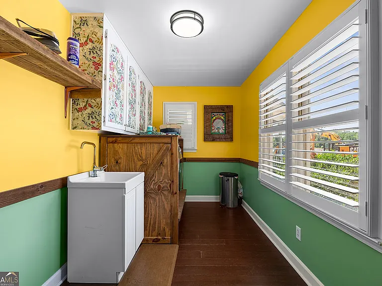 Laundry room with W/D, sink, storage cabinets, and shelving. Access from kitchen.