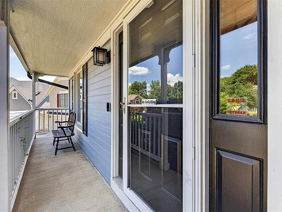 Covered front porch featuring light blue siding, white trim, and a black front door with an integrated window pane