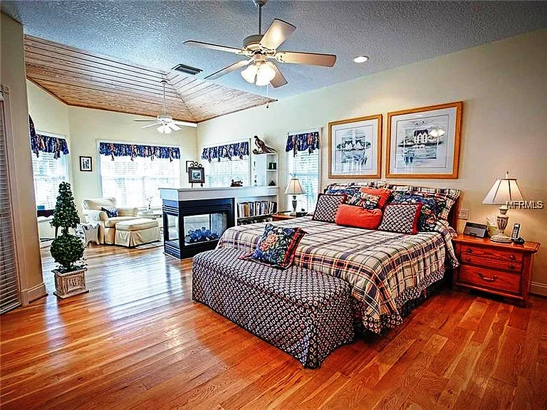 This is the master BR which connects with the Foyer and the main screened porch and overlooks the lake and the pool deck. It has a reading nook next to the windows that look out on the lake. The furniture and window treatments have been removed.