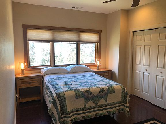 Bedroom. Ample closet space, desk, nightstands with lamps, and an additional utility closet with a washer and dryer. Ceiling fan.