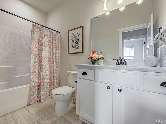 Just steps away is this lovely full bath with Shaker cabinet and quartz counter top. 