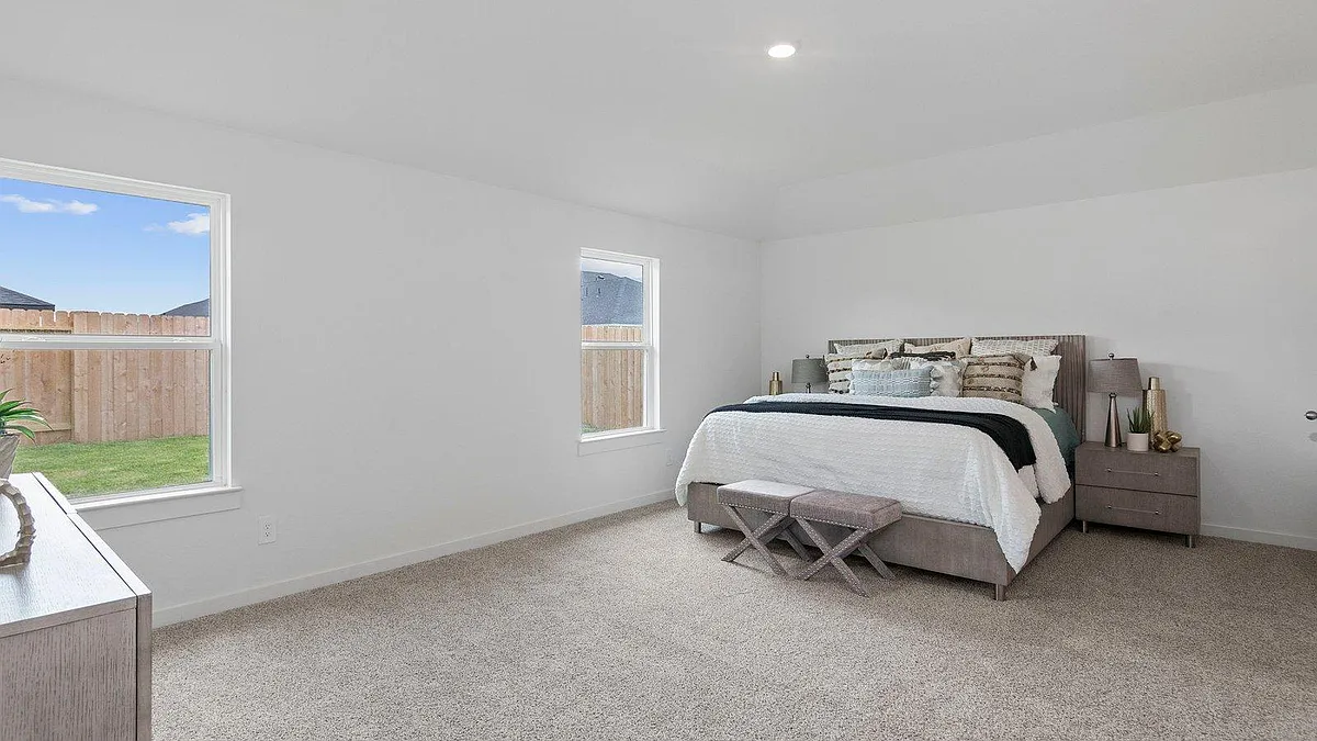 Photo 1 of 10 - Ambrose Peak Ln - Rosenberg, TX Spacious carpeted bedroom with two windows for natural light and ample wall space for storage and a desk setup. - Ambrose Peak Ln