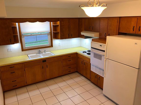 Kitchen with honey hardwood cabinets for ample storage, electric stove, exhaust fan, oven and fridge.