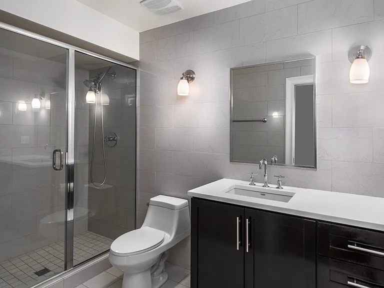 York House design bathroom with quartz countertops, oversized custom shower with glass doors and floor-to-ceiling tile.