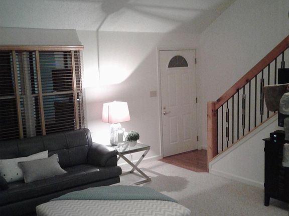 living room w/wooden blinds, carpet and custom stair rails
