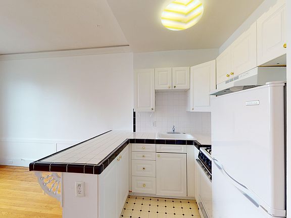 Kitchen with cabinets, a tiled countertop, a sink, a gas stove, and a refrigerator, set against wood flooring