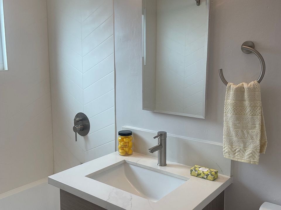newly renovated with herringbone detail on shower surround, quartz countertop and new fixtures