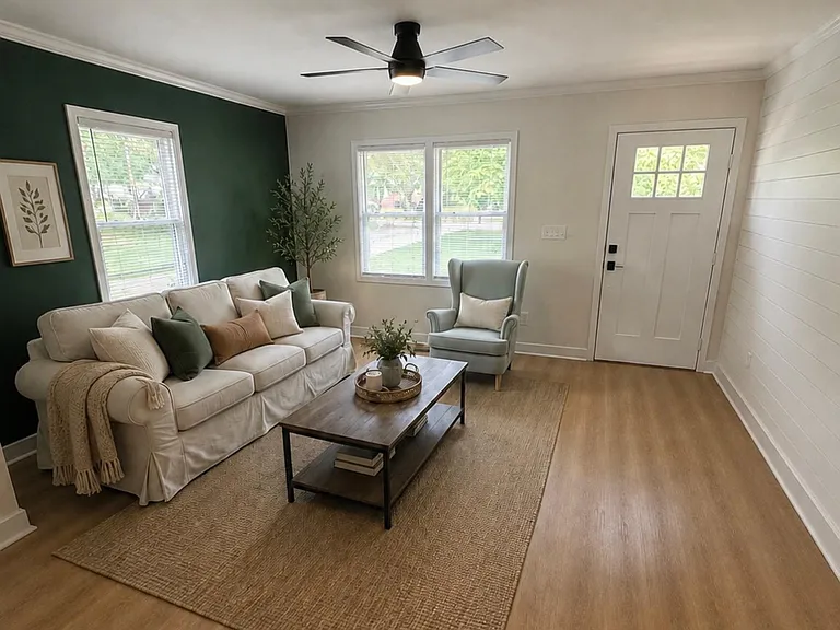 Welcoming living room with large windows, ceiling fan, and comfortable seating anchored by a coffee table and area rug.