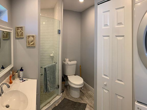 Modern new bathroom with glass shower door and subway tile. New washer and dryer in unit.