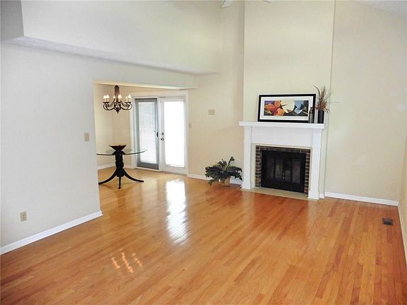 The Great Room features hardwood flooring, soaring ceilings, a wood-burning fireplace and ceiling fan