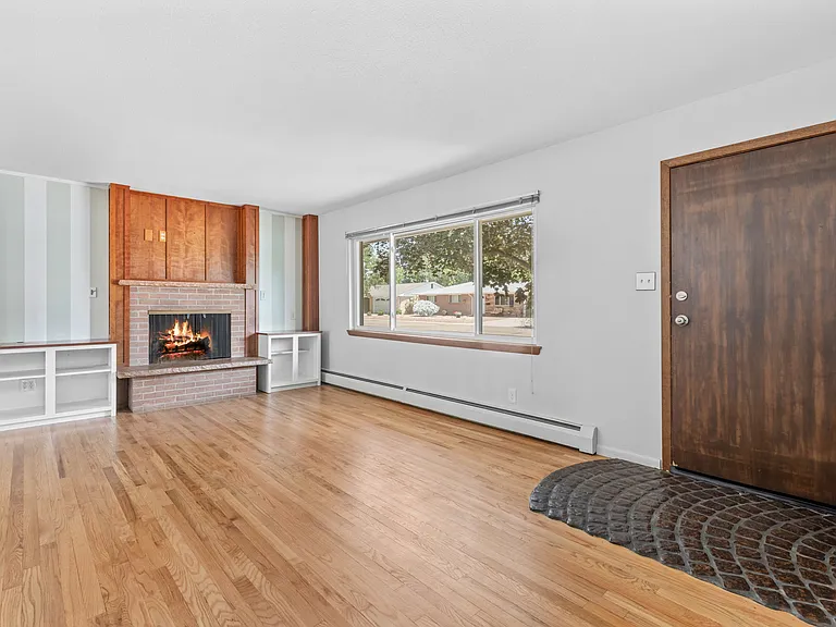 Step inside to a spacious living room featuring hardwood flooring, a cozy wood-burning fireplace and lots of natural light.