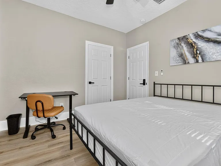 Furnished bedroom with bed frame, work desk and chair, plus two closets for convenient storage.