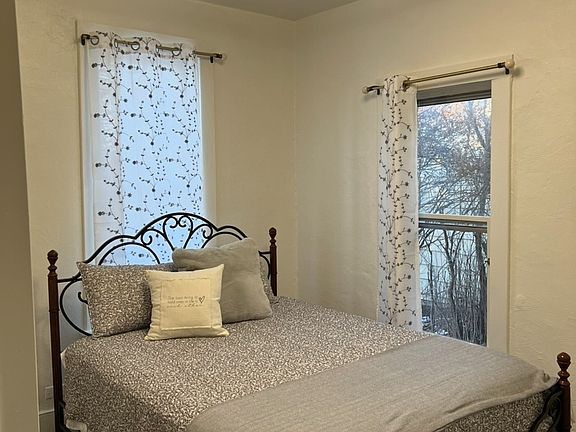 queen bed, accent chair, built in dresser, tv, and bedding