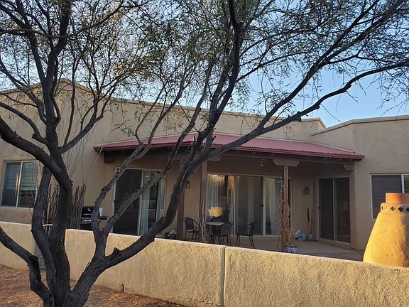 Rear of the house opens to greenbelt paths. Covered patio. Kiva fireplace and benches in the yard.