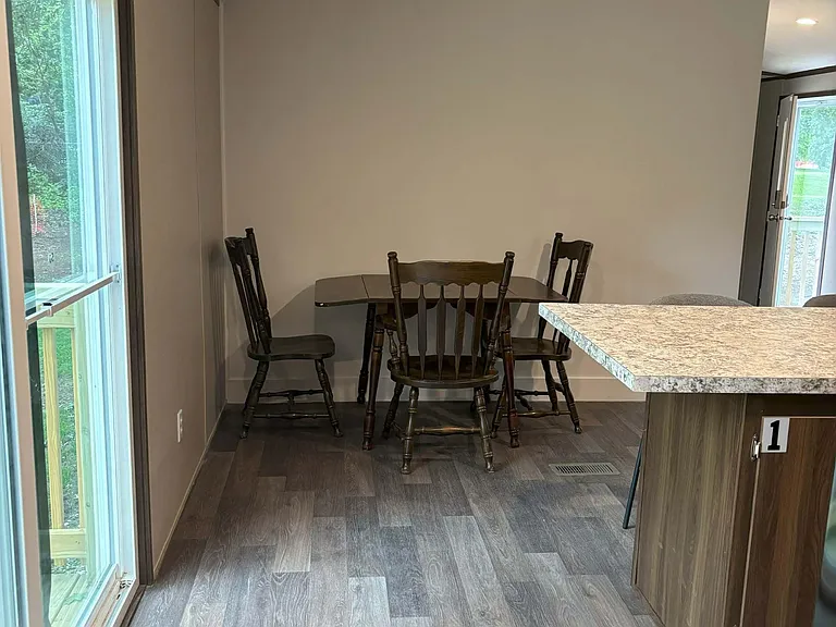 Dining nook with a table and chairs, set beside a large window and near the kitchen peninsula with easy outdoor access.