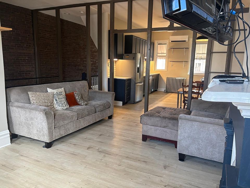 Livingroom featuring (non-functional) fireplace, built in adjustable shelving, windows looking out the front of the house, ceiling fan, and closet. Couches and TV included