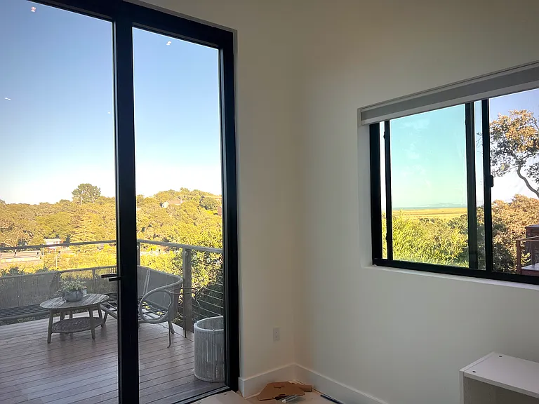 Office with tall glass window door accessing front deck