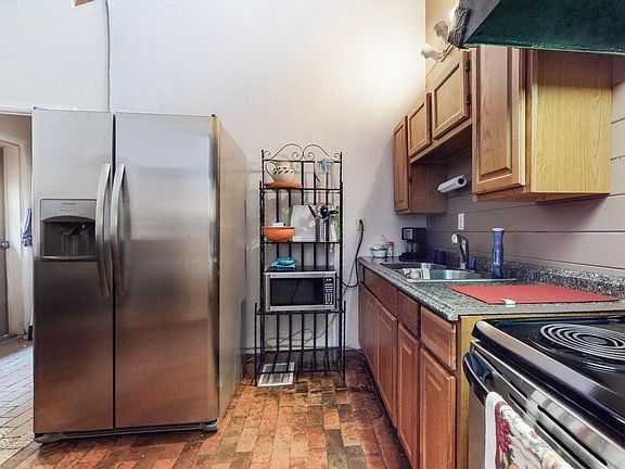 Kitchen with a table that seats four. Microwave, Stove, Electric Range, and stainless steel refrigerator.