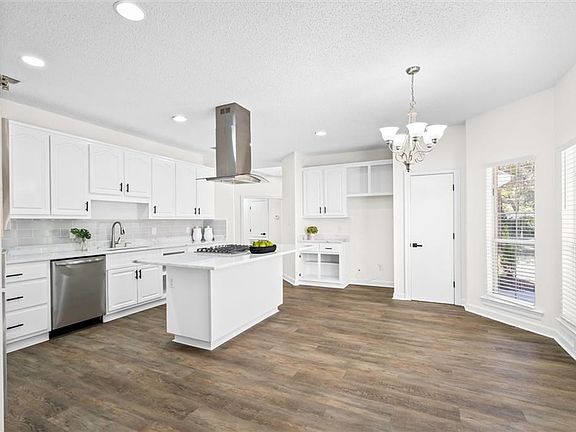 Kitchen featuring island exhaust hood, a kitchen island, decorative light fixtures, stainless steel appliances, and dark hardwood / wood-style flooring