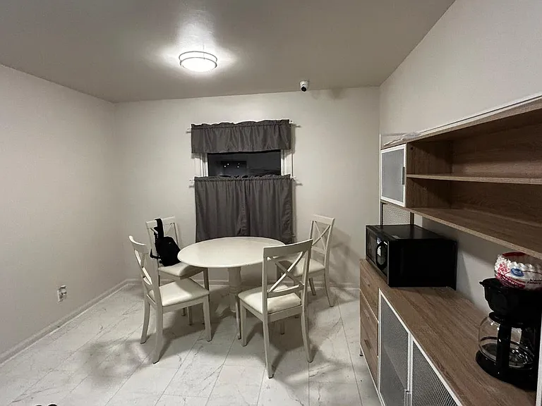 Dining nook with a round table seating four, plus built-in shelving and countertop space for small appliances.