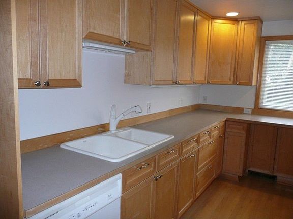 Upstairs kitchen is wrapped with oak cabinets and deep double sink. Easy care hardwood floors lead to eating bar at end overlooking the yard.