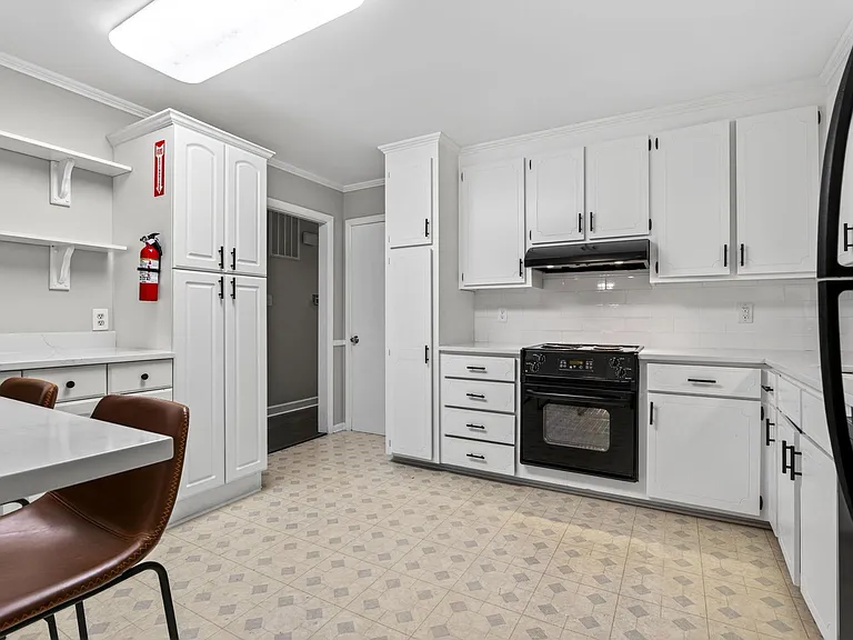Spacious kitchen with abundant white cabinetry, subway-tile backsplash, full-range oven, and ample counter workspace.