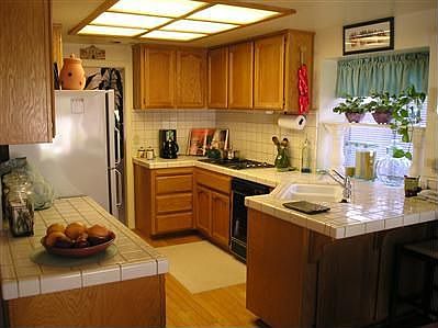 A WELL LIT KITCHEN AREA WITH PLENTY OF COUNTER SPACE AND AREA FOR A BREAKFAST BAR.