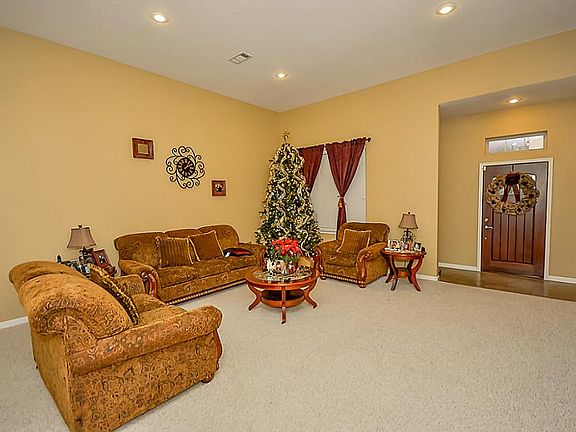 Living room with 12' ceilings and ceiling fan. Berber carpet.