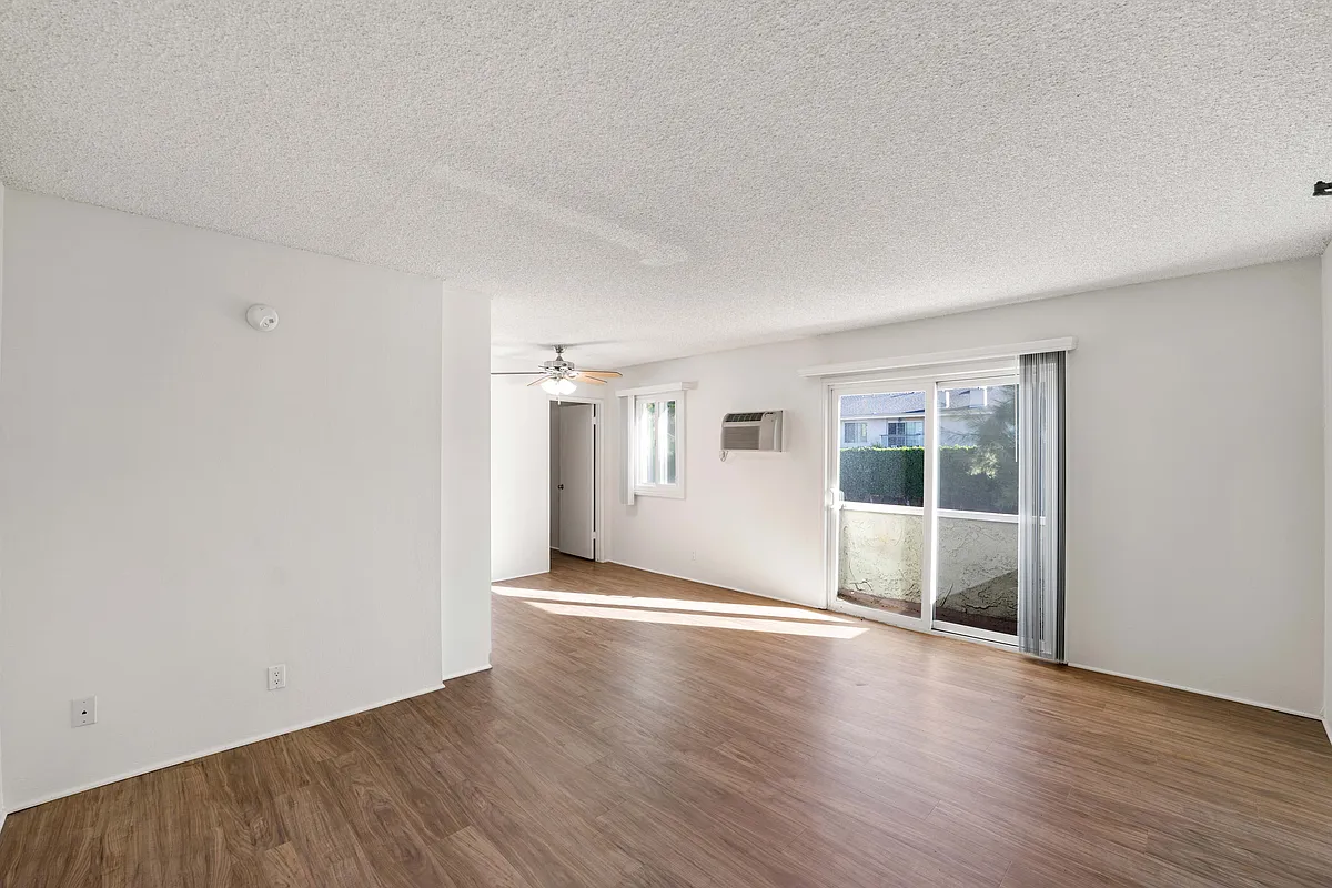 Sun-filled living space with wood-style floors and a private patio at Excelsior Apartments in Studio City. - The Excelsior