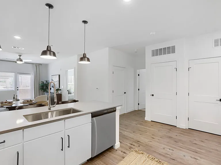 Open, bright, and built for entertaining. The B2 kitchen island with quartz countertops and stainless sink flows seamlessly into the dining and living areas.