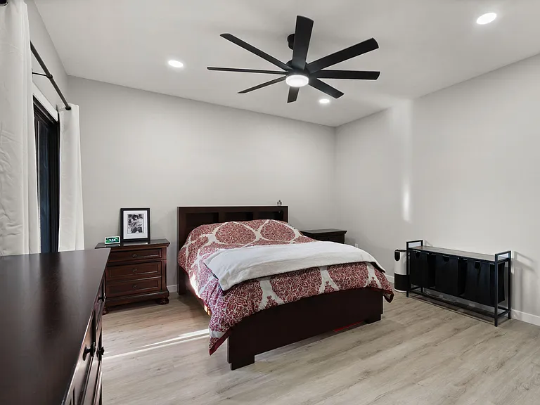Spacious bedroom with a ceiling fan, recessed lighting, and a furnished layout including bed, dresser, and nightstand.