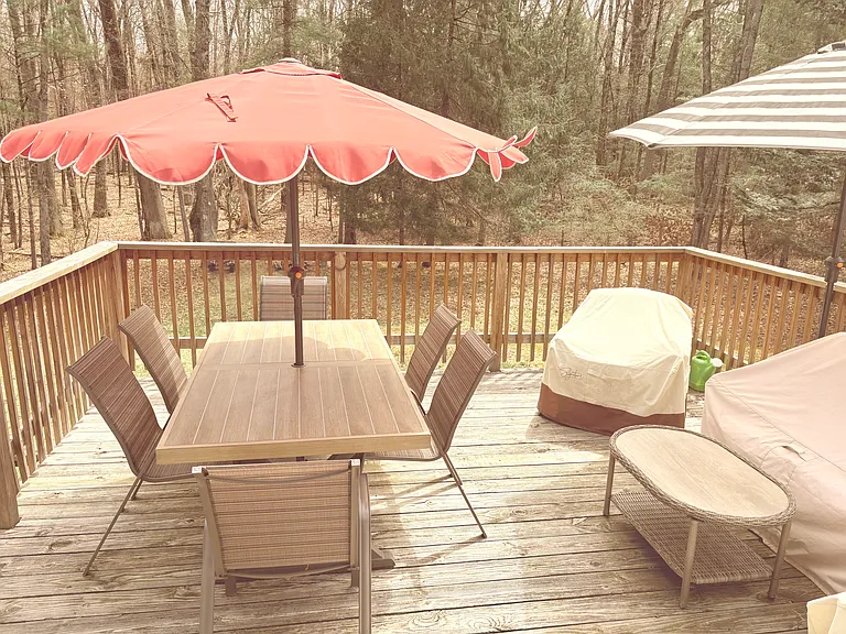 Spacious deck with a dining area for six and comfortable outdoor furniture, including a sofa, two chairs, and two umbrellas. It's a favorite spot for families to relax, share meals, and enjoy the fresh air.