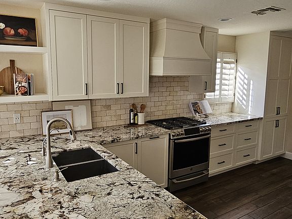 Granite countertops, stainless steel appliances, custom wood cabinets and gas range stove.