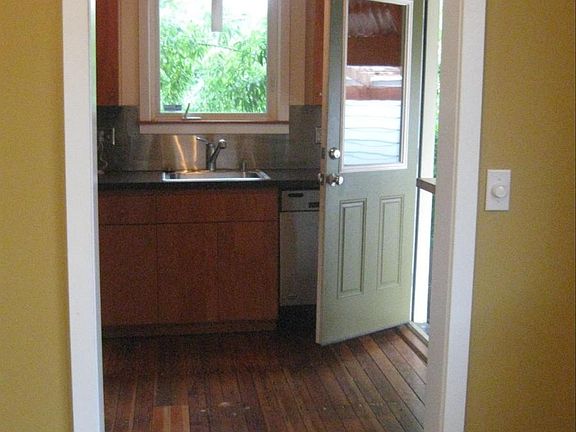 View front room into kitchen and side door to covered patio.