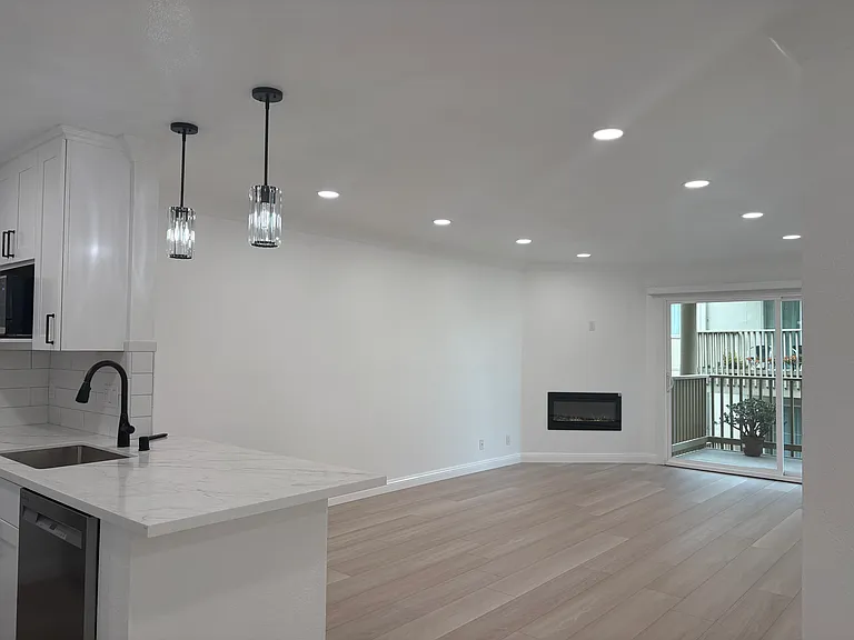 Main view walking into the unit: Luxury Vinyl Flooring throughout, and an electric fireplace. Large sliding glass doors bathe the open-concept living area that provide direct access to an oversized deck, extending your living space outdoors.