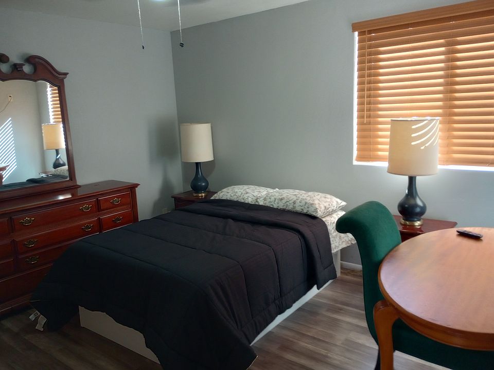 Clean bedroom with new bedding , dresser, desk and nightstands.