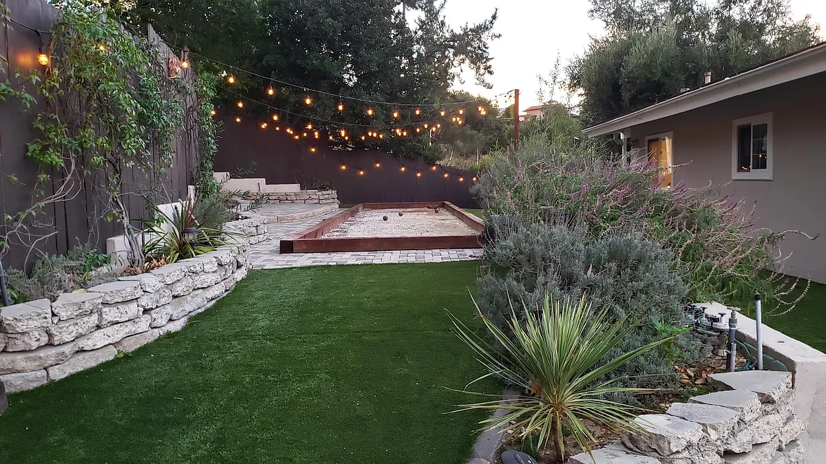 Backyard with Bocce Court and low maintenance landscaping with artificial grass and live plants peppered in. - 18610 Paseo Nuevo Dr