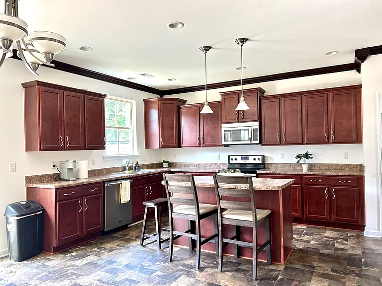 Spacious kitchen with ample cabinetry, breakfast bar seating, and stainless appliances including range and microwave.