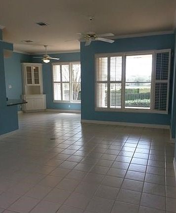 High ceilinged, open living area looking into breakfast room. Plantation shutters.