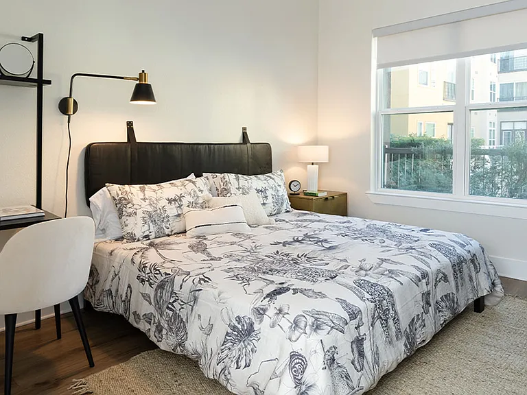 Spacious apartment bedroom with wood-style flooring.
