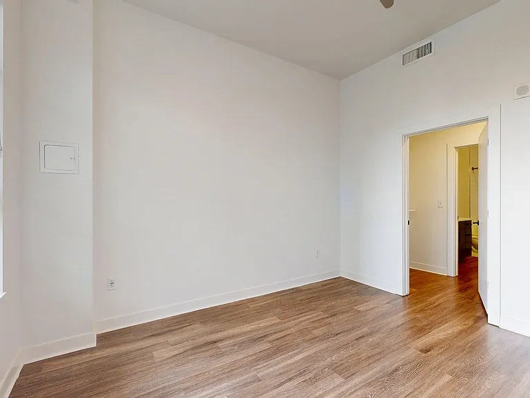 Spacious apartment Bedroom with Plank Flooring and Attached Bathroom.