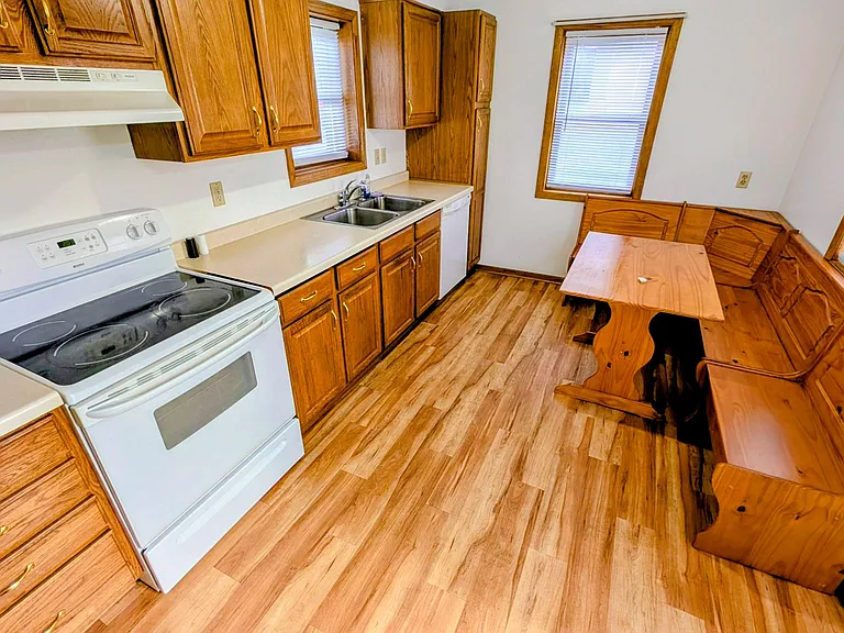 Eat-in kitchen with ample wood cabinetry, laminate counters, electric range, dishwasher, and a double-basin sink.